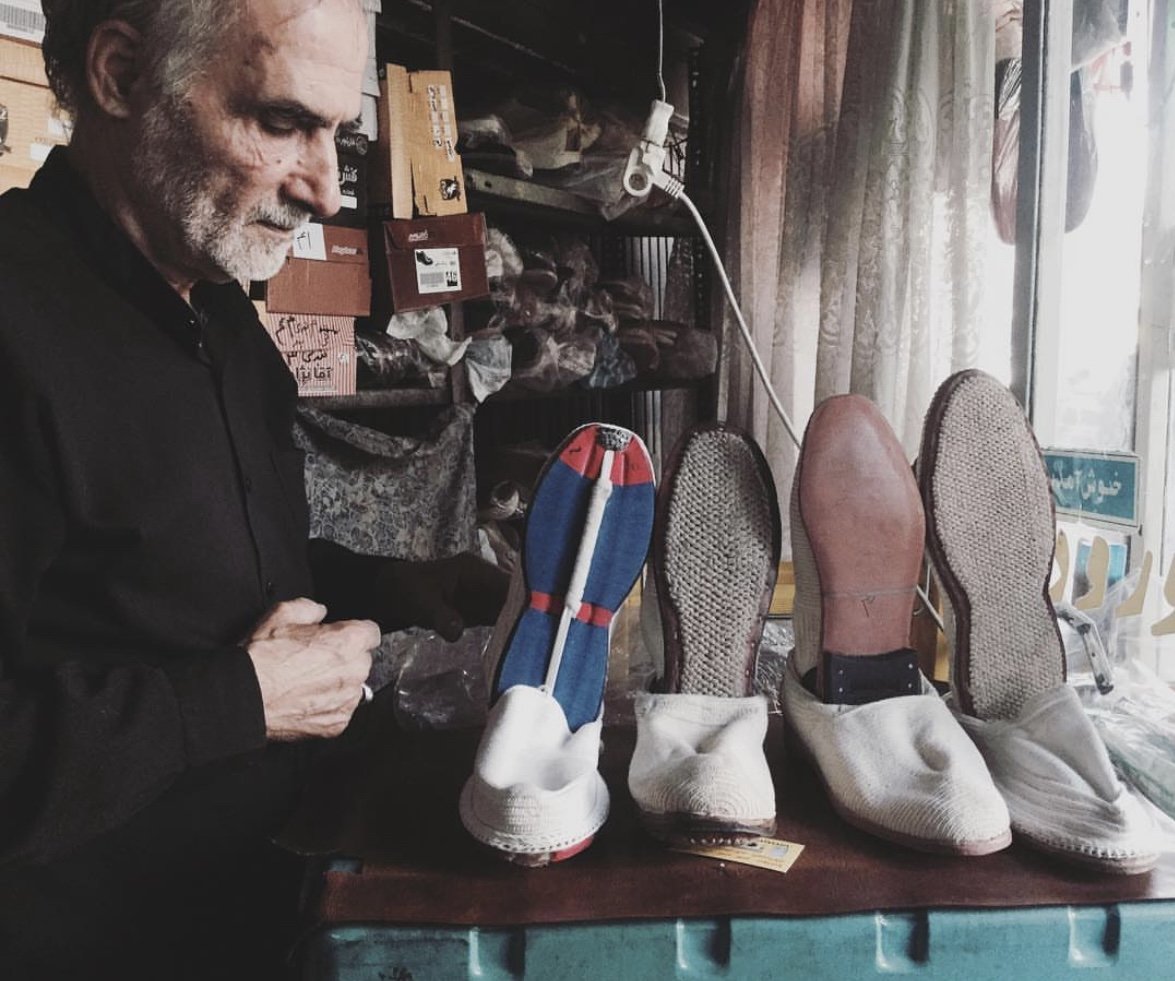 Un artisan et plusieurs modèles de pâpouches aux semelles différentes, dans son échoppe