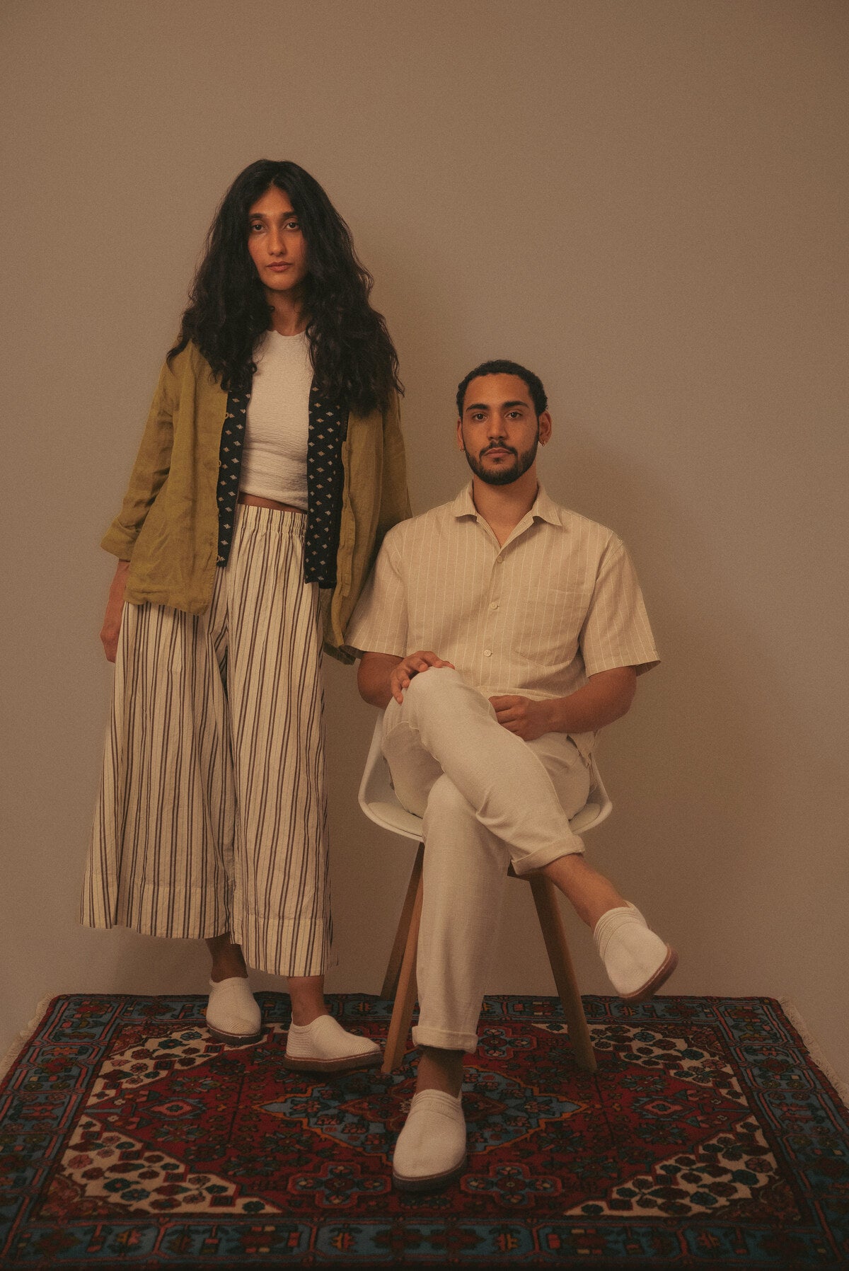 Couple en studio, pâpouches écrues sur tapis persan