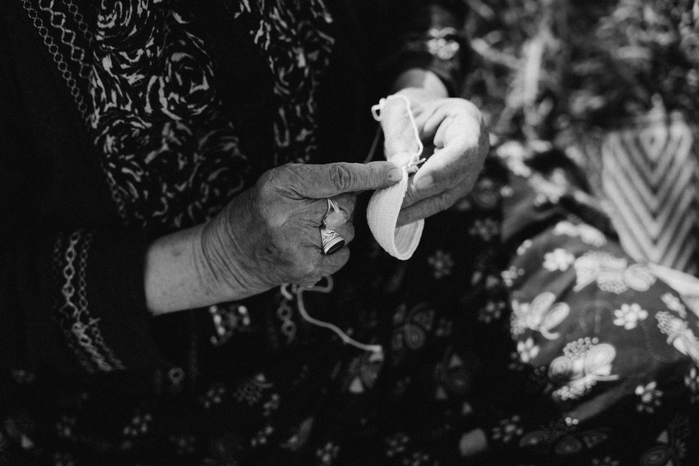 Les mains d'une aînée crochetant la tige d'une pâpouche, en clair-obscur